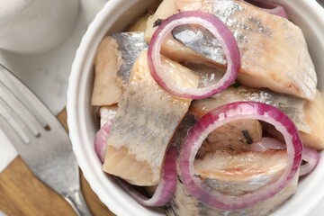 Pieces of delicious herring with onions on white table, closeup