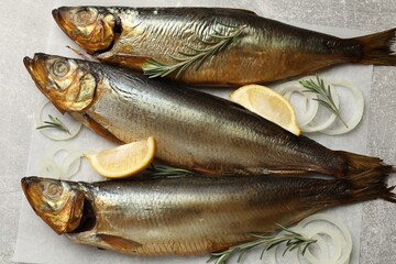 Smoked herrings, onion, rosemary and lemon on light grey table, top view