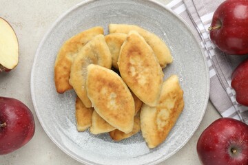 Delicious fried pyrizhky (stuffed pies) and apples on light grey table, flat lay