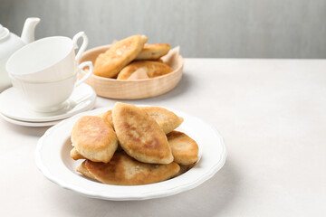 Delicious fried pyrizhky (stuffed pies) on white table, closeup. Space for text