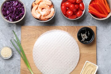 Rice paper sheets and different ingredients on light grey table, flat lay