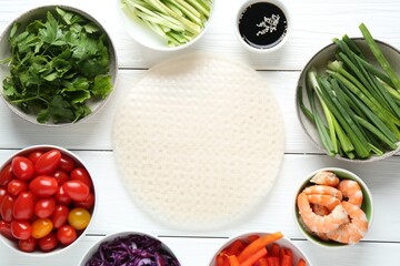 Rice paper sheets and different ingredients on white wooden table, flat lay