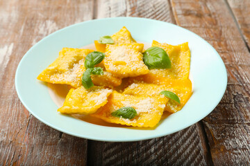 Delicious ravioli with cheese and basil on wooden table, closeup