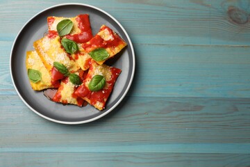 Delicious ravioli with tomato sauce, parmesan cheese and basil on blue wooden table, top view. Space for text
