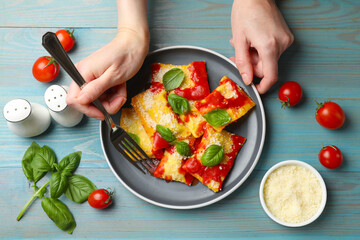 Woman eating delicious ravioli at blue wooden table, top view