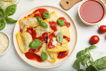 Delicious ravioli with tomato sauce, parmesan cheese and basil on white table, flat lay