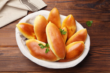 Tasty baked patties and parsley on wooden table, top view
