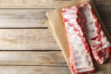 Raw pork ribs on wooden table, top view. Space for text