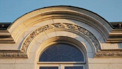 Obraz premium The image depicts an architectural detail of a stone building. The focus is on the ornate window and the intricate carvings along its edges, showcasing the craftsmanship and historical significance.