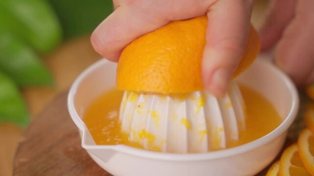 Hand juicing an orange half on manual citrus squeezer