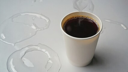 Coffee mug with liquid, surrounded by splashes and drops on white surface.