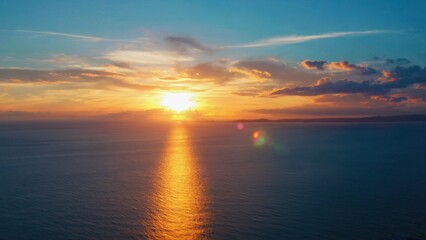 Naklejka premium Peaceful sunset over the ocean, with a reflection on the water and clouds above. A beautiful beach scene.