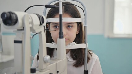 A young girl undergoing an eye examination using medical optometry equipment. The image represents the importance of regular vision screening and healthcare.