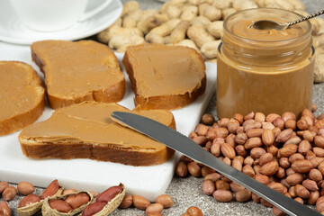 Fresh bread with peanut butter among peanuts. Delicious healthy breakfast.