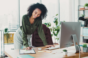 Young professional woman working at her desk in a bright and modern office space, engaging with...
