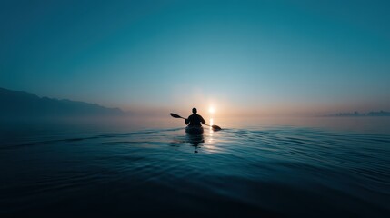 Fototapeta premium A young man navigates a kayak on a serene lake in the early morning. The sun rises, illuminating the mist, creating a peaceful atmosphere perfect for reflection and calmness