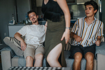 Obraz premium A group of friends enjoying time together on a cozy sofa. The atmosphere is casual and relaxed, emphasizing friendship and leisure in a homey environment.