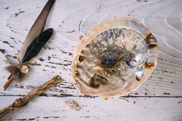 Burning sweetgrass (Hierochloe odorata) in an iridescent abalone shell on an old white wooden...