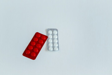 Two blister packs, one red and the other white with tablets, on a white background, choice of medications, different tablets, expired medicines, placeholder for text, mockup.