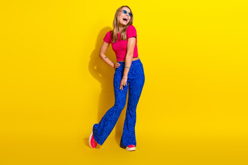 Energetic young woman in stylish outfit posing against bright yellow backdrop, showcasing confidence and vibrant fashion trends