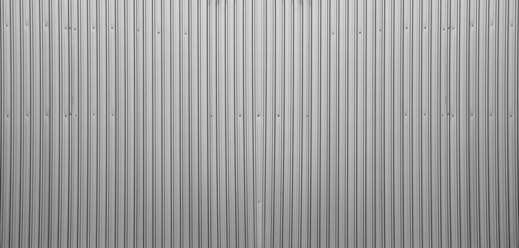 Silver tin iron corrugated wall with horizontal stripes from a metal profile of a metal sheet. Texture, background. grey wall fence texture for backdrop galvanized gray facade.