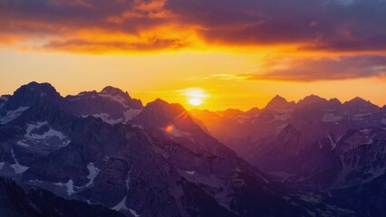 Stunning sunset in the mountains, showcasing majestic peaks silhouetted against a vibrant sky.