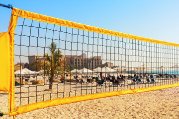 Volleyball net on the beach. Beautiful view of  beach volleyball court with blue summer sky,  palm trees, hotel.