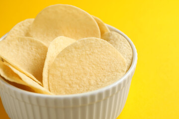 Tasty potato chips on yellow background, closeup