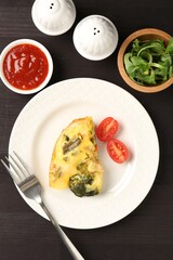 Tasty vegetable casserole served on black wooden table, flat lay