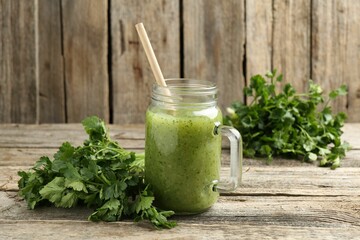 Healthy parsley smoothie in mason jar and leaves on wooden table, closeup