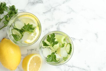 Healthy drink with parsley, cucumbers, lemon and celery on white marble table