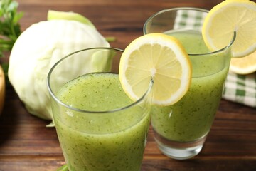 Healthy parsley drink in glasses, lemons and cabbage on wooden table, closeup