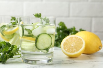 Healthy drink with parsley, cucumbers, lemons and celery on white marble table, closeup