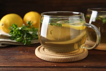 Healthy parsley tea with lemon slices on wooden table, closeup. Detox drink