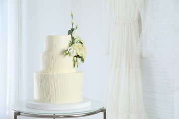 Delicious wedding cake with floral decor on table indoors, space for text