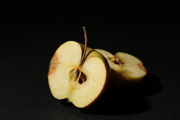 Halves of overripe apple on black background, closeup