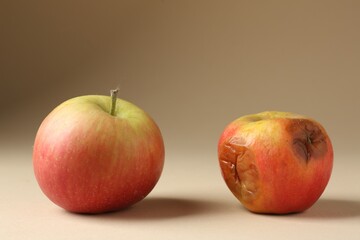 Rotten and fresh apples on beige background, closeup