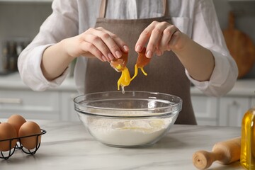 Making khinkali. Woman adding egg into bowl at table in kitchen, closeup