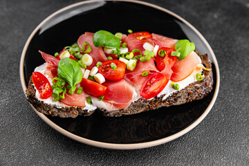 Bruschetta ham, tomato, greens dish fresh delicious gourmet food background on the table rustic food top view copy space