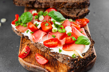 Bruschetta ham, tomato, greens dish fresh delicious gourmet food background on the table rustic food top view copy space