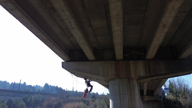 Rope access technician inspecting highway overpass concrete structure