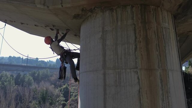 Height worker repairing concrete bridge pillar