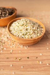 Hemp seeds in wooden bowl on wooden table, top view. Superfood, natural organic seeds for healthy eating, source of protein, vitamins and omega 3. Healthy food concept