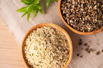 Hemp seeds in wooden bowl on wooden table, top view. Superfood, natural organic seeds for healthy eating, source of protein, vitamins and omega 3. Healthy food concept