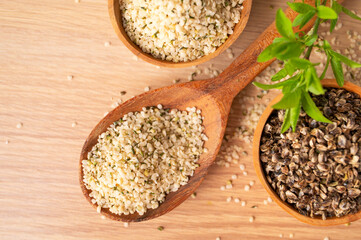 Hemp seeds in wooden spoon and bowls on wooden table, top view. Superfood, healthy tasty organic hemp seeds, source of omega 3 fatty acids, protein. Supplement to healthy diet