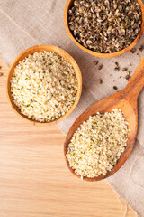 Hemp seeds in wooden spoon and bowls on wooden table, top view. Superfood, healthy tasty organic hemp seeds, source of omega 3 fatty acids, protein. Supplement to healthy diet