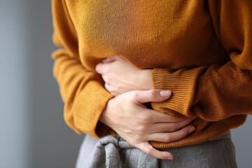 Woman in Mustard Sweater Holding Abdomen: A Quiet Moment of Discomfort