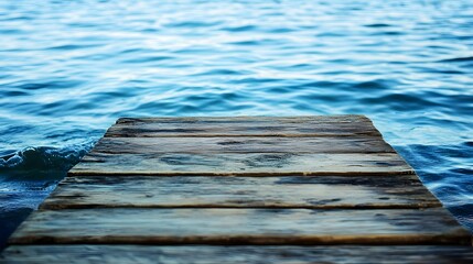 Fototapeta premium Wooden dock extends into blue water surface creating a sense of tranquility.