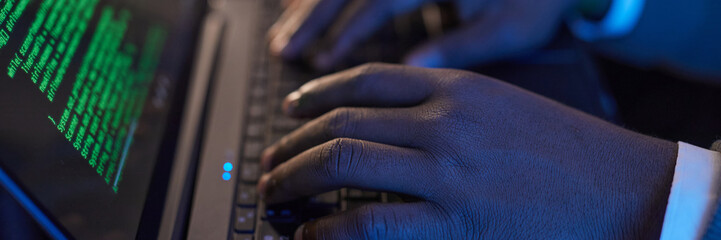 Website header shot of hands typing on a laptop keyboard with green code displayed on screen, emphasizing technology and coding process