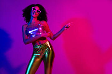 Naklejka premium Trendy young woman dancing in vibrant neon light, radiating glowing charm and style